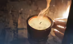 the smoke from a lit candle is rising in a cup