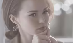 an attractive woman leaning her chin on her hand while looking into the camera