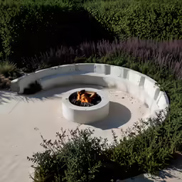 a circular concrete fire pit in the middle of a garden