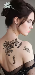 a young woman has a back tattoo that depicts flowers and vines