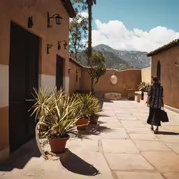 a woman walking up the side walk of an adobe house