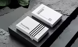 two white business cards on a black and grey surface