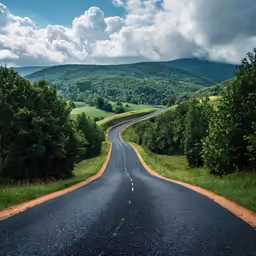 an empty road in the middle of mountains with green trees