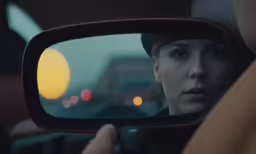 there is a person that has stopped in the car and is reflected by the mirror