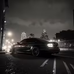 a black car driving down a street at night