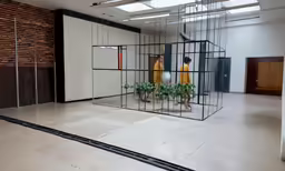 a pair of people standing behind bars in an empty room