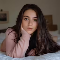 a beautiful young woman laying on top of a bed