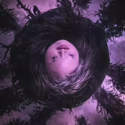 a girl looking up into the sky with a bird nest overhead