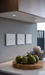 green fruit on wooden board sitting near three white plates and lights
