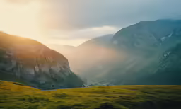 the sun setting over a beautiful valley, with mountain ranges in the background