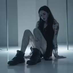 a woman sitting in the dark with no shoes