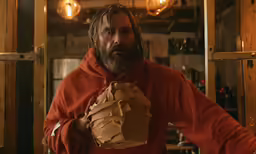 the man is holding food wrapped in paper