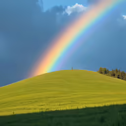 a double rainbow above the hill with some trees on top