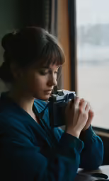 a woman sitting at a table holding a camera
