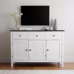 a white painted dresser next to a wall