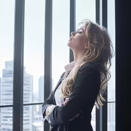 a woman with long blonde hair standing in front of a glass window