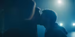 a man and woman kissing under bright lights