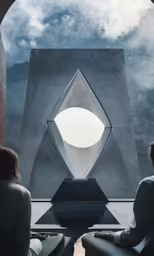 two woman sitting next to each other looking at a sculpture
