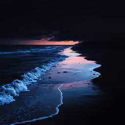 a black beach with waves coming in on the shore