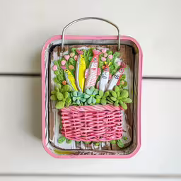 a pink basket that has various plants in it,a wicker basket with pink handles holding fruit and drinks