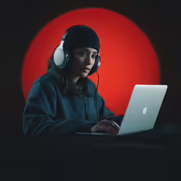 a person with headphones on sitting with a laptop computer