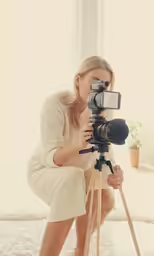 a woman kneeling down and taking pictures on a tripod