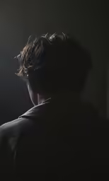 a man stands in the dark looking at a street light