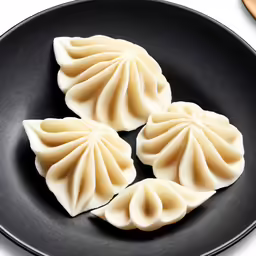 three dumplings of white cheese on a black plate