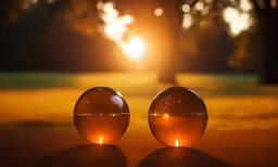 two sphere candles are on the ground near the grass