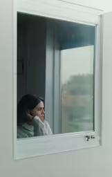 a girl with earbuds in front of window