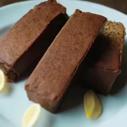 there are pieces of cake with dark frosting on the plate
