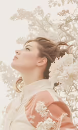 woman with hair blown back under the flowers of a tree