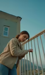 a woman leaning against a white metal fence
