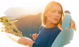 a woman standing on top of a hill holding a surfboard