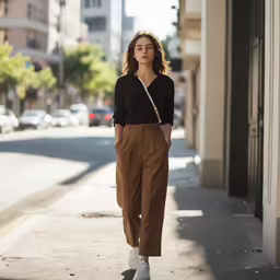 woman wearing brown pants and white shoes on a sidewalk