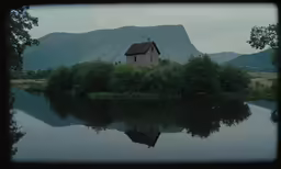 a house and lake in front of some mountains