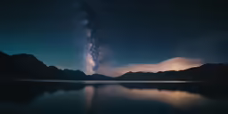 a night sky with stars over water and mountains