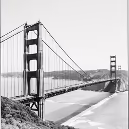 a black and white image of a long bridge over water