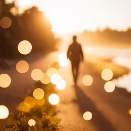 a person walking down the road with sun setting behind them