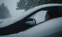 a young woman sitting in a car covered in snow