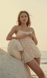 a beautiful young woman standing on a rock