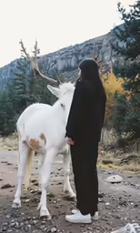 the woman is petting a goat in the wilderness