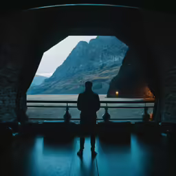 man standing in dark room near mountain with lights on