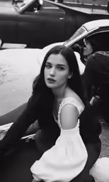 a woman sitting on the ground near a car