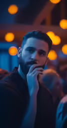 man in dark shirt holding finger to mouth