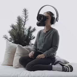 a woman sitting on top of a bed wearing headphones