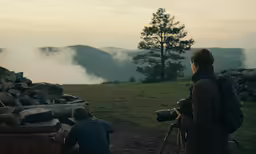a man on top of a hill with a camera