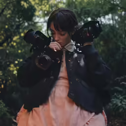 a woman holds her camera up to their shoulders