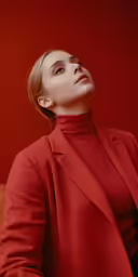 a woman in a red top and jacket poses for a photo