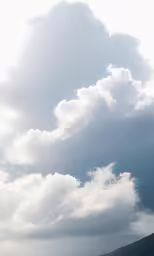 a cloudy sky with sheep grazing on a hill in the foreground